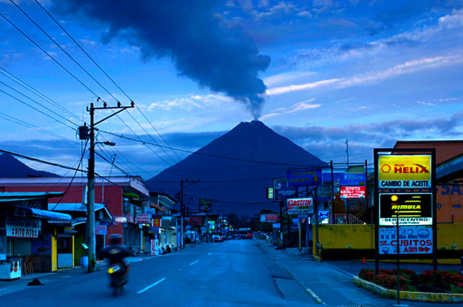 The very active Arenal Volcano looms over the town of La Fortuna, Costa Rica at dawn.